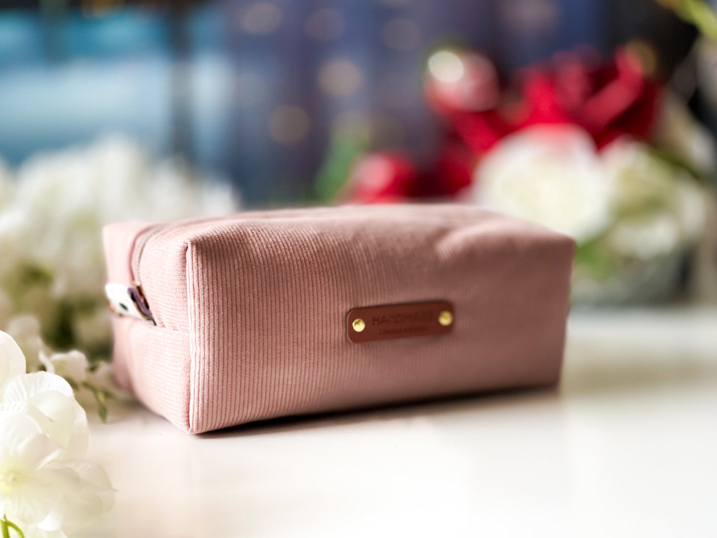 Pink toiletry bag with a brown tag on a blurred background