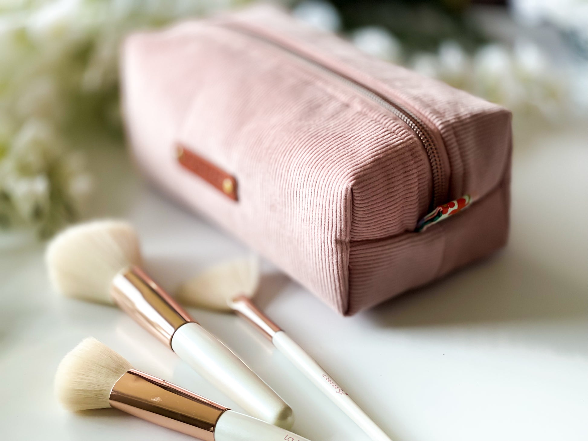 Pink makeup pouch with brushes on a light background