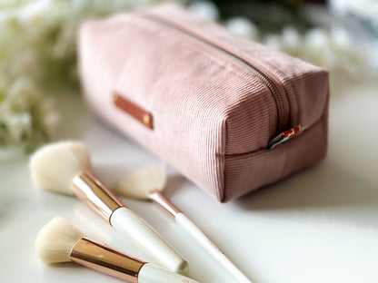 Pink makeup pouch with brushes on a light background