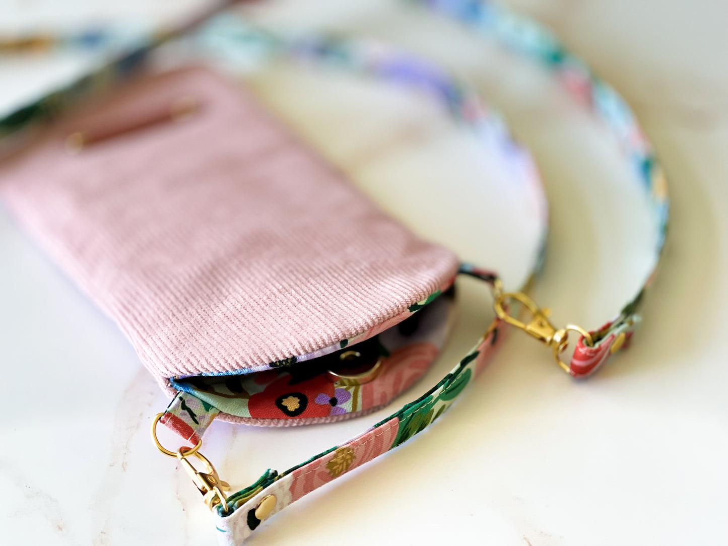 Pink phone case with a colorful strap on a light background