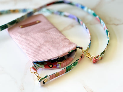 Pink wallet with a colorful strap on a light background