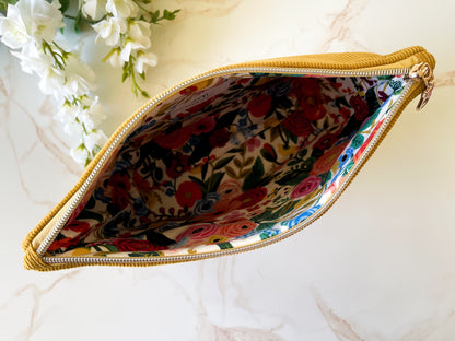 Floral-patterned pouch with a gold zipper on a marble surface.
