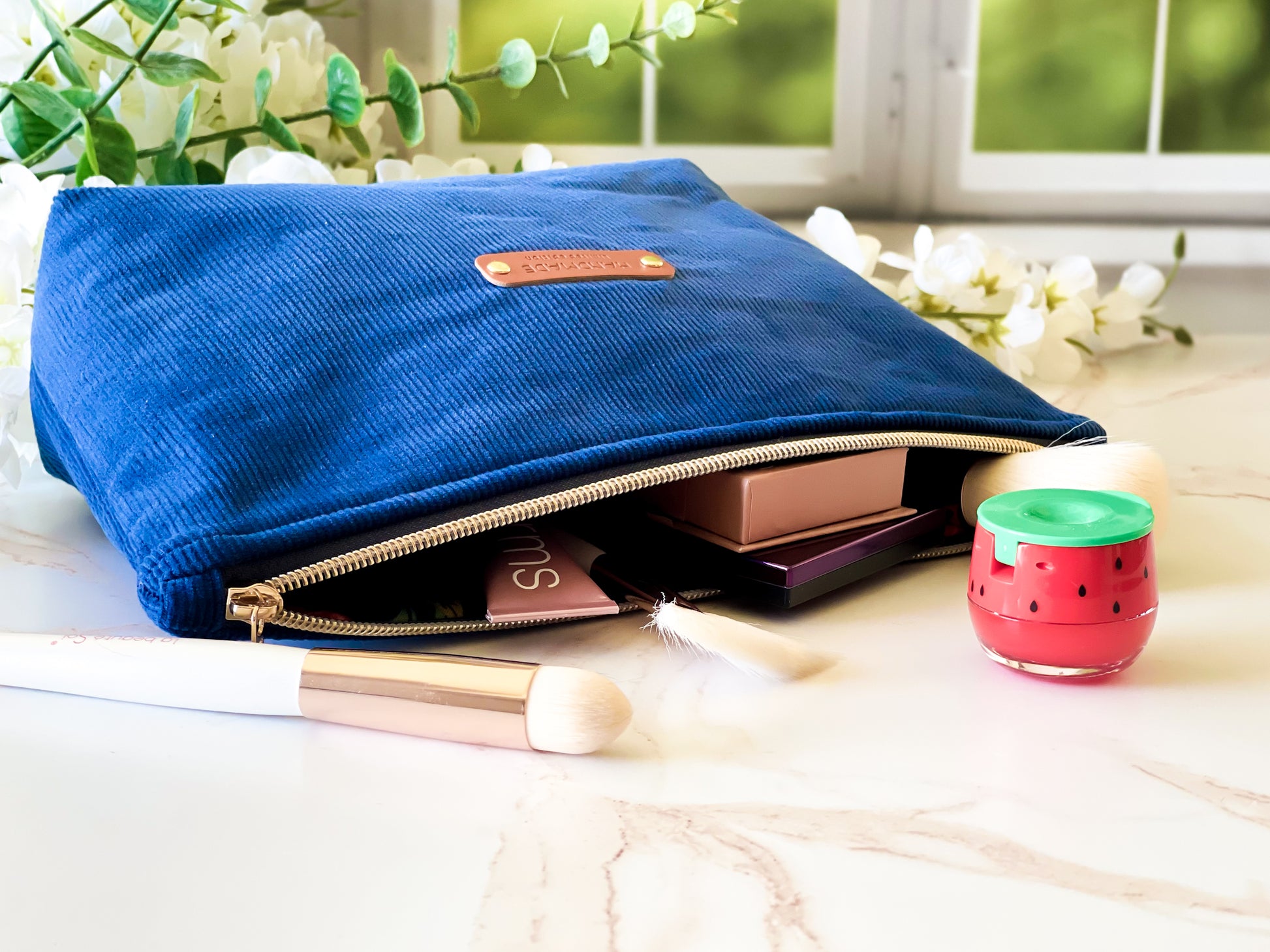 Blue makeup bag with cosmetic items on a light surface