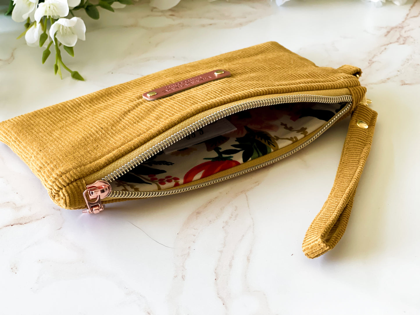 Yellow clutch bag with floral interior on a marble surface
