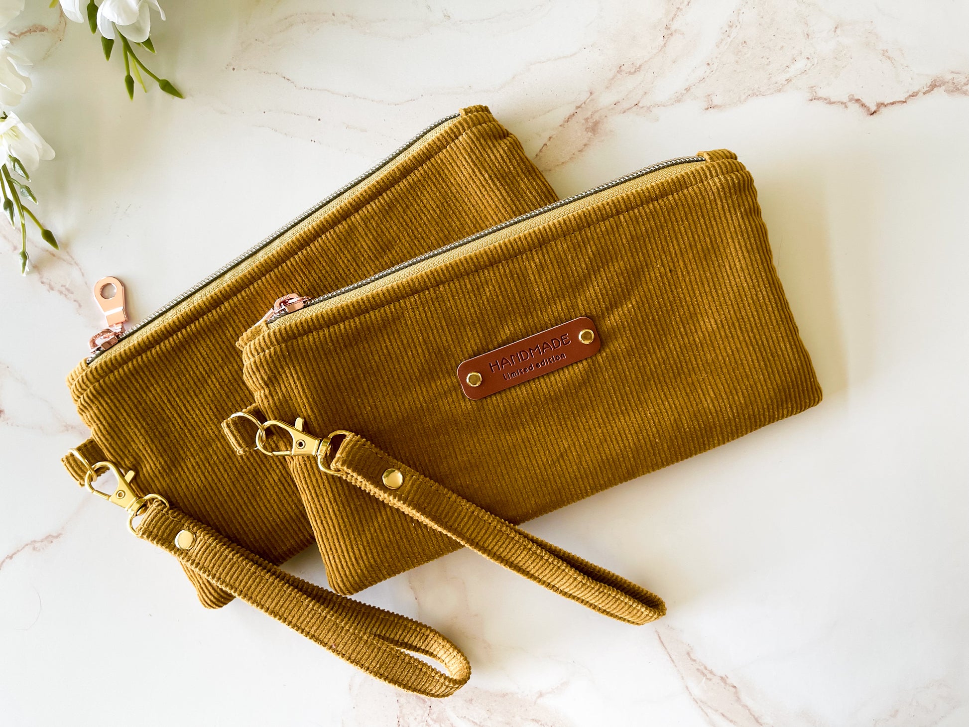 Two mustard yellow handbags with a visible brand label on a marble surface.